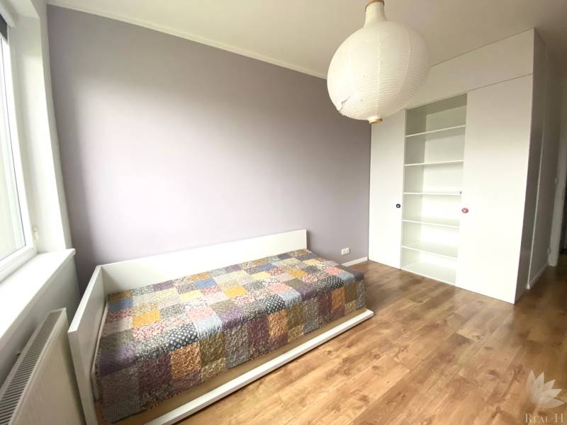 Gyerekszoba egy háromszobás lakásban, ággyal és fa dekorációjú padlóval.