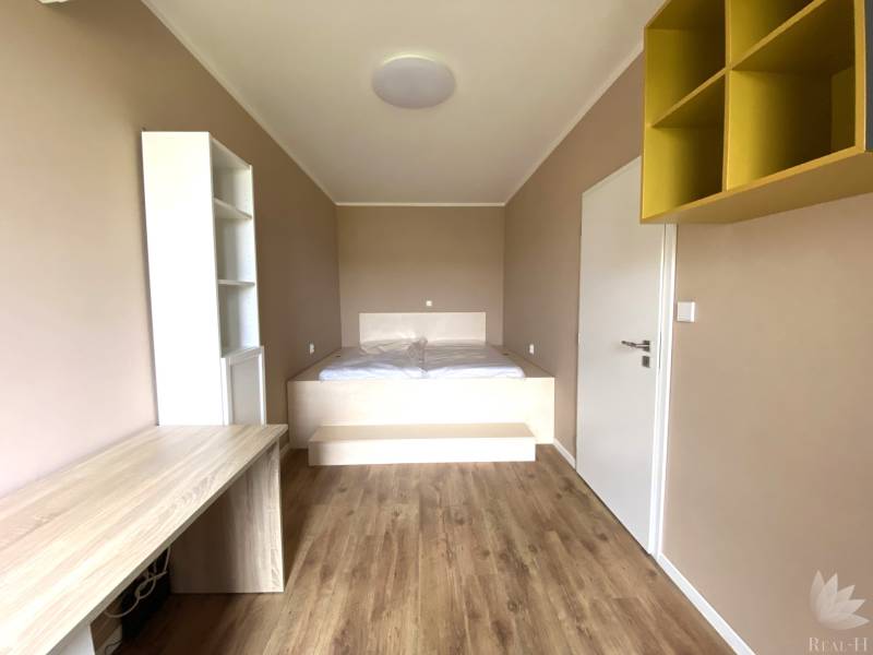 Szoba egy háromszobás lakásban fa dekor padlóval és beépített asztallal.