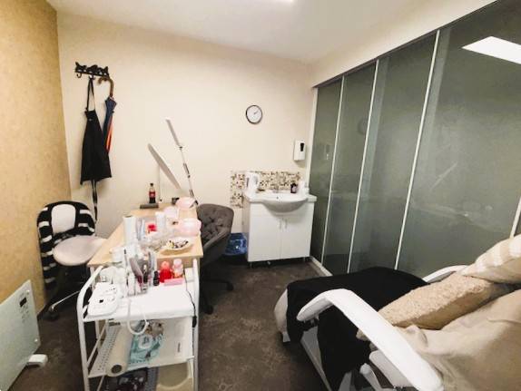 Kozmetikai szalon székkel, asztallal és mosdóval az üzlethelyiségben.