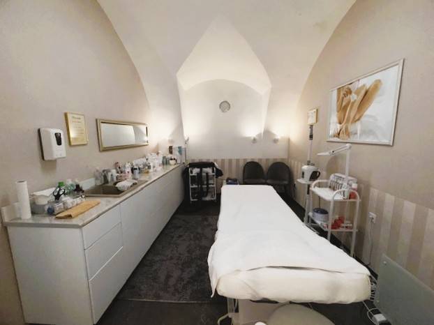 Üzlethelyiség masszázsággyal, gyógyászati segédeszközökkel és dekoratív képpel a falon.