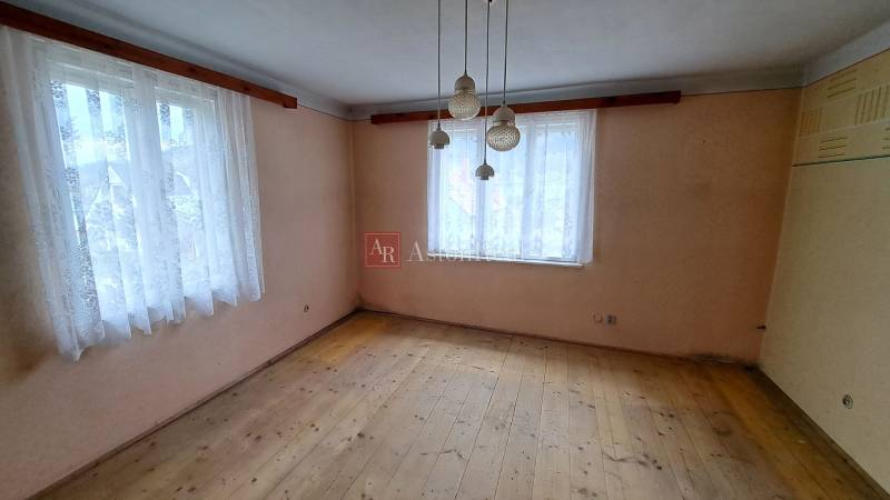 Szoba egy családi házban két ablakkal és fa dekorációjú padlóval.