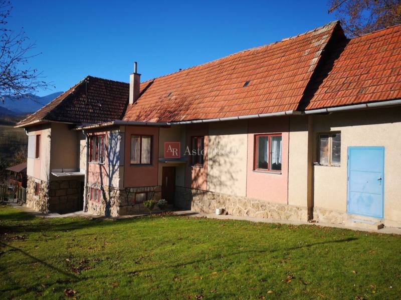 Családi ház Kalamenyben, Rózsahegyen, piros tetővel és kék ajtókkal.