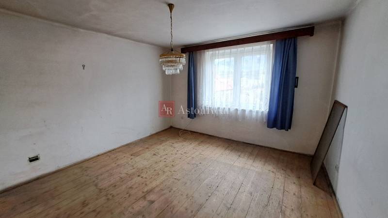 Szoba egy családi házban fa mintázatú padlóval, függönyökkel és csillárral.