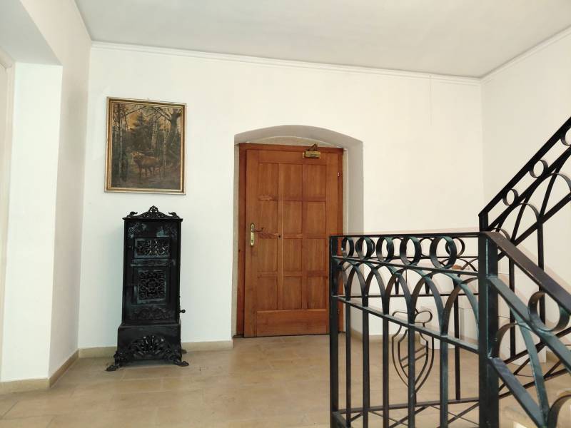 Iroda folyosója festménnyel, faajtókkal és cserépkályhával.