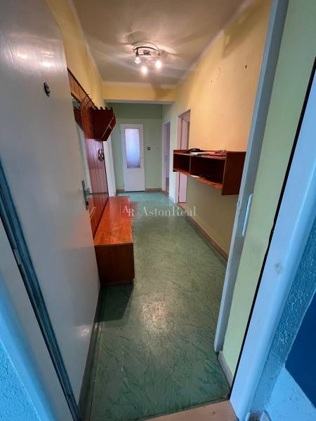 Folyosó egy 3 szobás lakásban beépített bútorokkal és zöld padlóval.