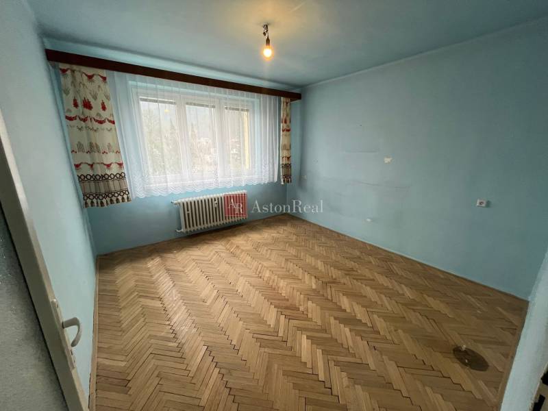 Kék szoba nagy ablakkal és fa dekorációjú padlóval egy háromszobás lakásban.