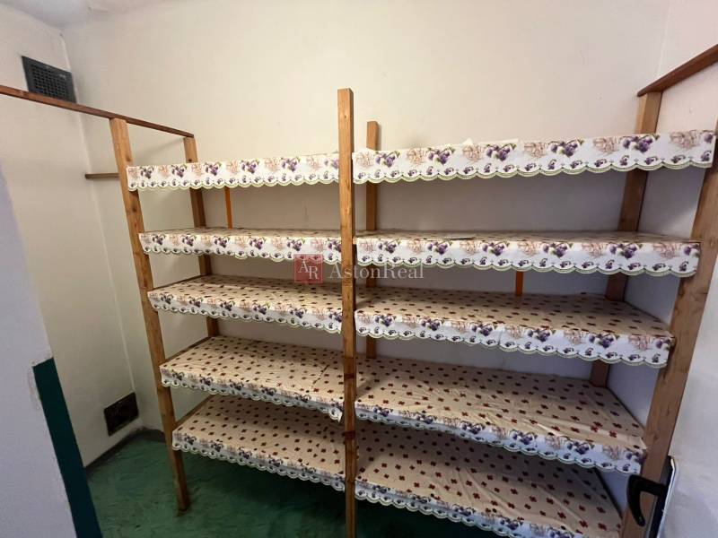 Tárolóhely egy háromszobás lakásban fa polcokkal és zöld padlóval.