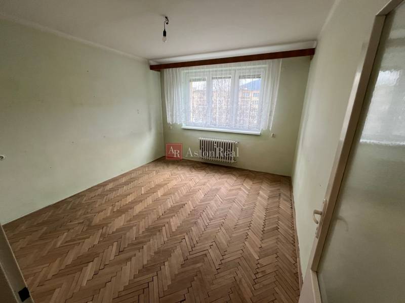 Szoba egy háromszobás lakásban fa dekorációjú padlóval és nagy ablakkal.