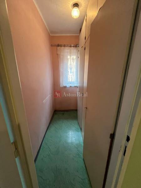 Keskeny szoba beépített szekrénnyel és függönnyel egy háromszobás lakásban.