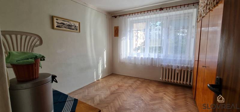 Szoba ablakkal és fa dekorációjú padlóval egy háromszobás lakásban.