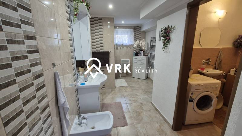 Fürdőszoba családi házban csempézett fallal, bidével, mosógéppel és dekorációkkal.