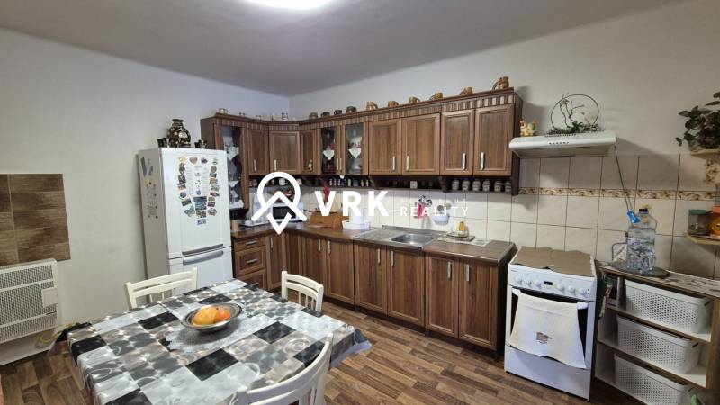 Konyha családi házban konyhabútorral, étkezőasztallal és fa dekoros padlóval.