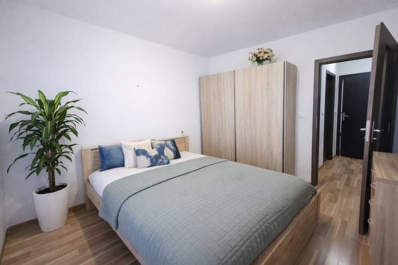 Hálószoba egy kétszobás lakásban ággyal, szekrénnyel és fa dekorációjú padlóval.