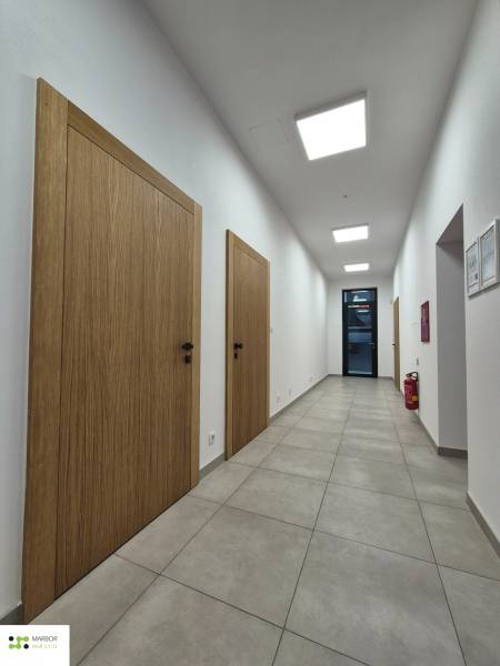 Folyosó világos csempékkel, faajtókkal és mennyezeti lámpákkal egy egyszobás lakásban.