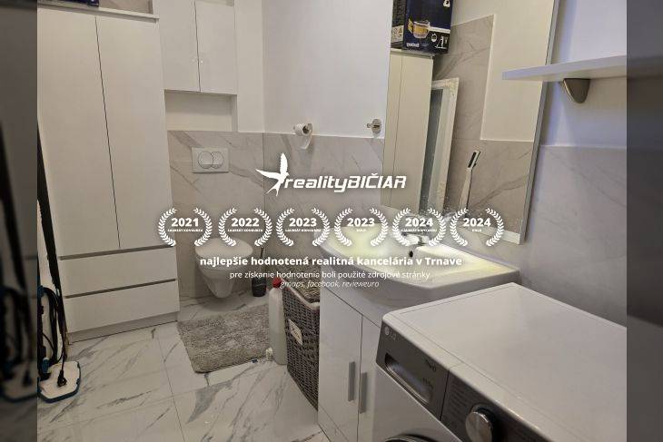 Fürdőszoba üdülőapartmanban mosógéppel és márvány dekorációjú falakkal.