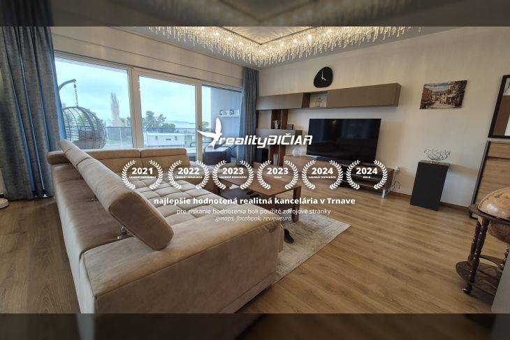 Nappali a nyaraló apartmanban kanapéval és fa dekorációjú padlóval.