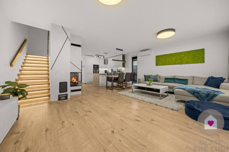 Nappali egy négy szobás lakásban, fa dekoros padlóval, kandallóval és modern lépcsővel.