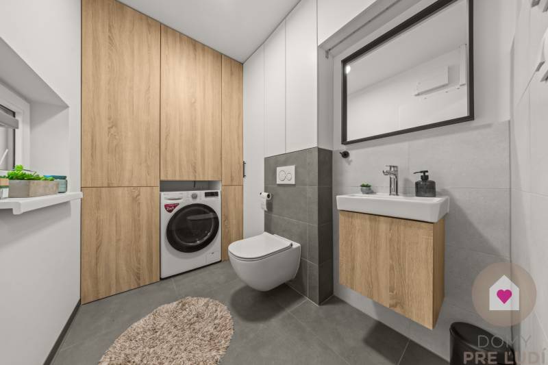 Fürdőszoba függesztett WC-vel, mosdóval és mosógéppel szekrényekkel a négy szobás lakásban.