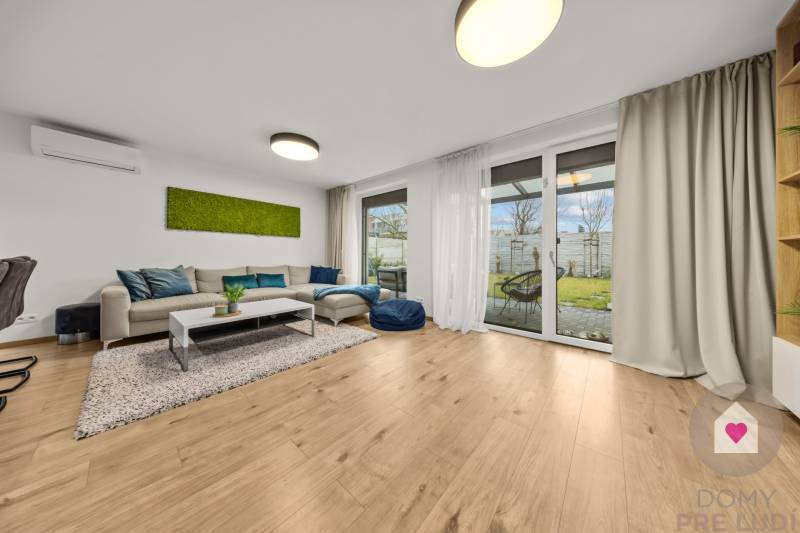 Nappali kanapéval, üvegajtókkal és fa dekorációjú padlóval egy négy szobás lakásban.