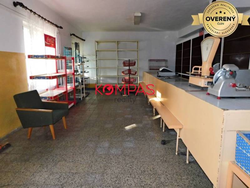 Kereskedelmi helyiségek belső tere pulttal, polcokkal és székkel.