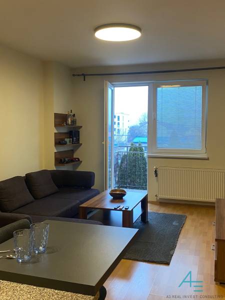 Nappali egy kétszobás lakásban kanapéval, asztallal és fa dekor padlóval.