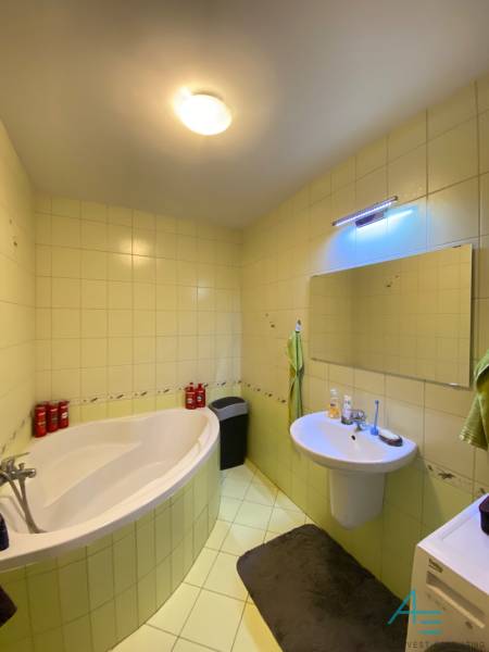 Fürdőszoba egy kétszobás lakásban káddal, mosdóval és tükörrel a falon.