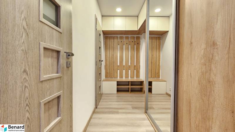 1 szobás lakás belső tere fa hatású padlóval, szekrényekkel és fogasfallal.