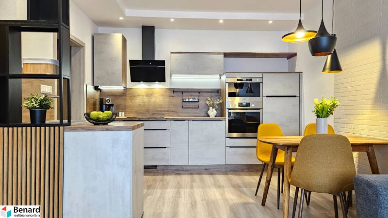 Konyha egy egyszobás lakásban fa dekor padlóval, étkezőasztal és sárga székek.