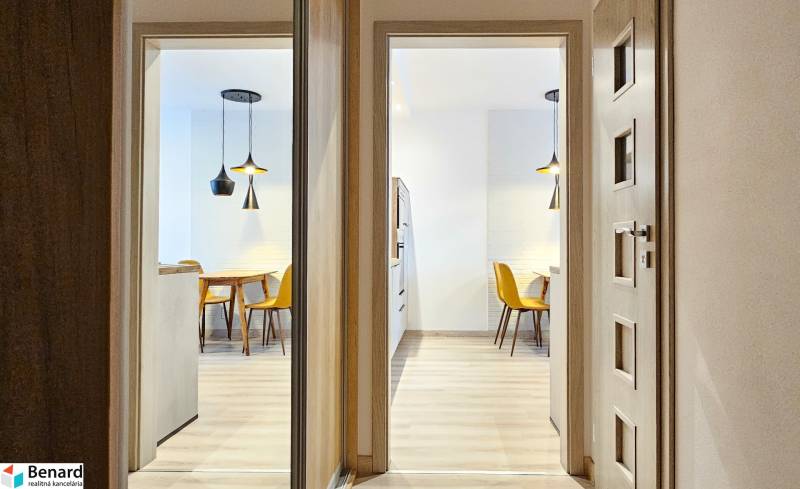 Világos étkező konyhaasztallal és sárga székekkel egy garzonlakásban.