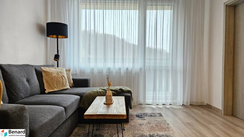 Stílusos nappali egy egyszobás lakásban kanapéval és asztallal fa dekorációjú padlón.