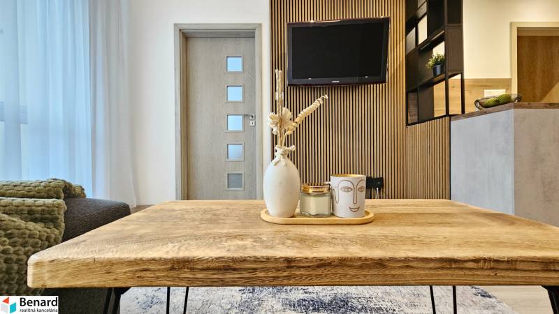 A nappali rész egy egyszobás lakásban faasztallal és dekorációkkal a háttérben egy televízióval.