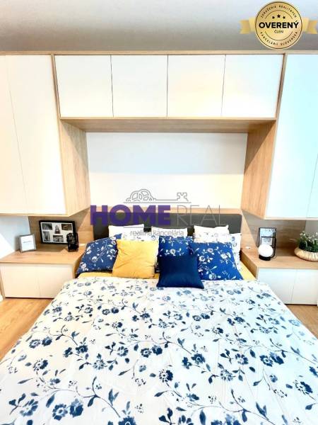 Hálószoba egy háromszobás lakásban fa dekor padlóval és virágmintás ágyneművel.