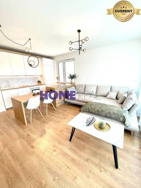 Nappali konyhával egy háromszobás lakásban, világos kanapé, fa dekoros padló.