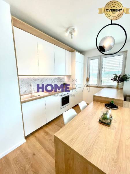 Konyha egy háromszobás lakásban fehér szekrényekkel és fa dekorációjú padlóval.