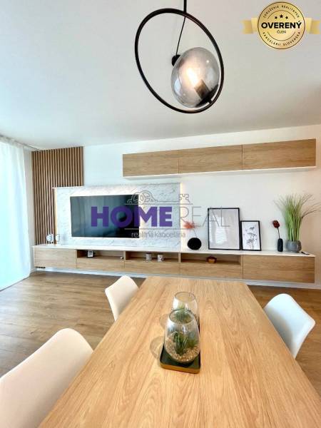 Világos nappali egy háromszobás lakásban, fa dekoros padlóval és modern vonalvilágítással.