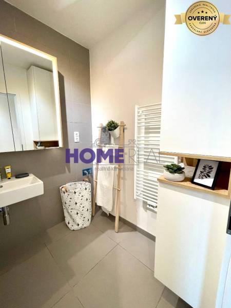 Fürdőszoba mosdóval, tükörrel és fehér radiátorral egy háromszobás lakásban.