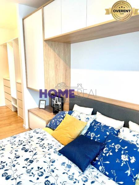 Hálószoba egy háromszobás lakásban ággyal, színes párnákkal és tárolóhelyekkel.