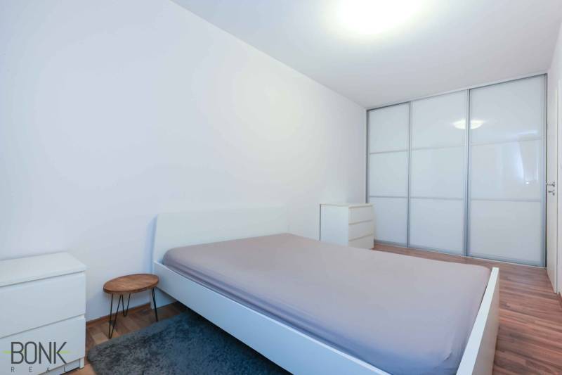 Hálószoba egy kétszobás lakásban nagy beépített szekrénnyel és fa dekorációjú padlóval.