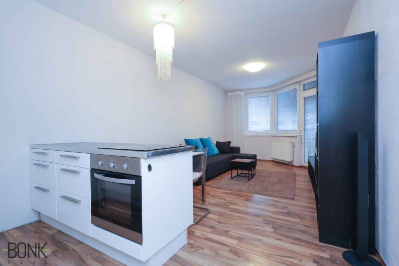 Konyhasarok és nappali egy kétszobás lakásban tűzhellyel és kanapéval.