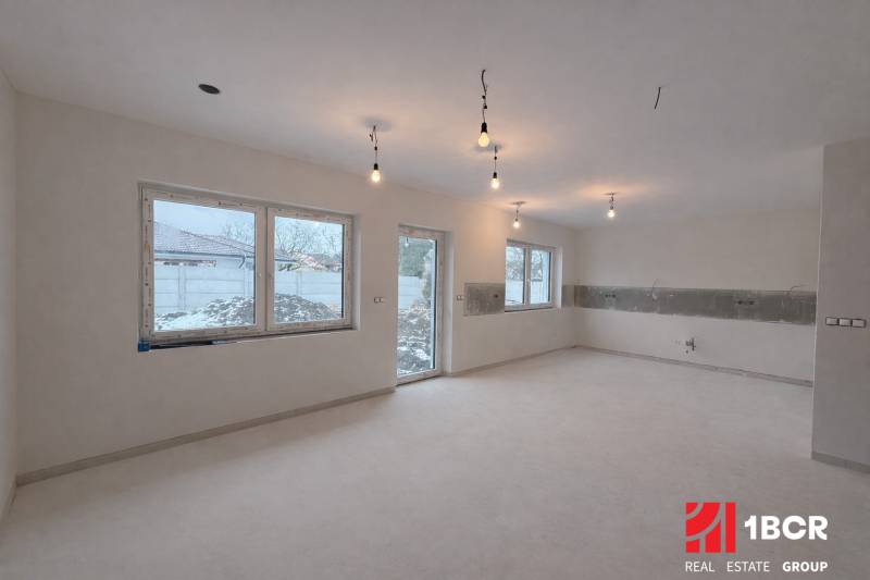 Családi ház belső tere világos padlóval és nagy ablakokkal, bútorok nélkül.