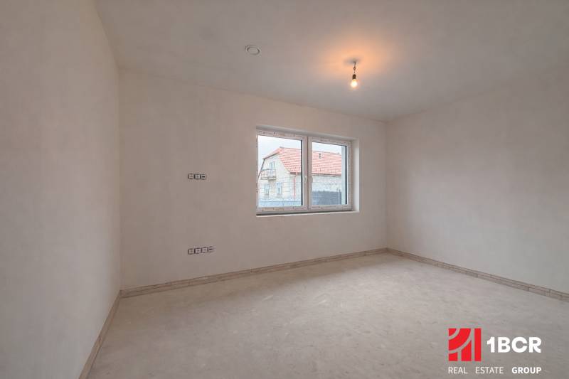 Tágas szoba egy családi házban, ablakkal, amely egy másik házra néz.