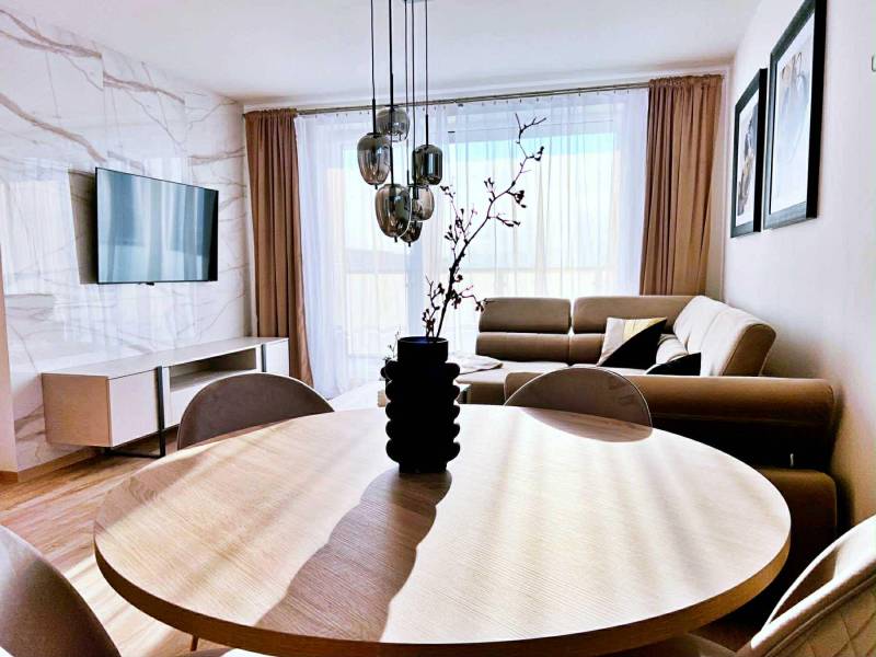 Nappali egy háromszobás lakásban, fa dekorációjú padlóval és kényelmes kanapéval.