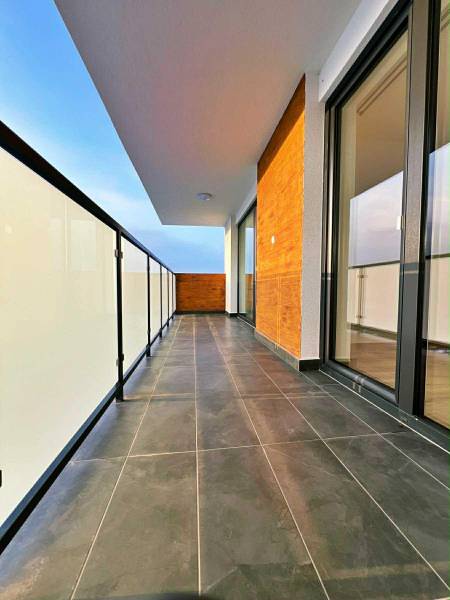 Biztonságos erkélykorlát és sötét burkolat a háromszobás lakás erkélyén.