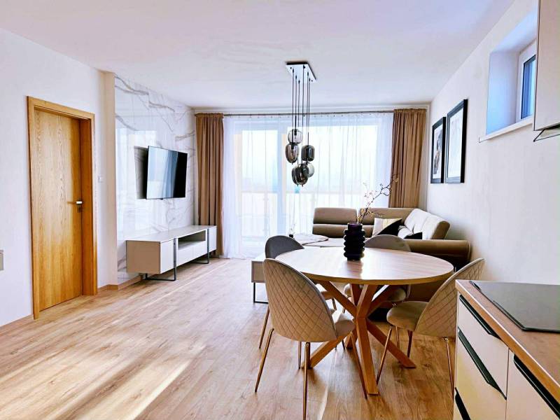 Nappali egy háromszobás lakásban világos bútorokkal és fa dekorációjú padlóval.