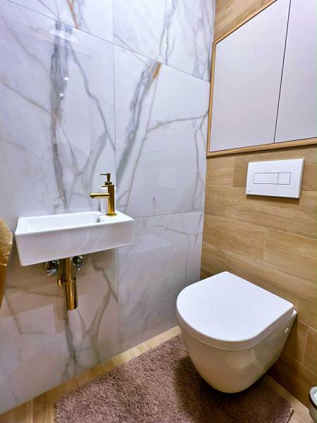 Fürdőszoba kerámia mosdóval, tükörrel és fa dekorációjú padlóval egy háromszobás lakásban.