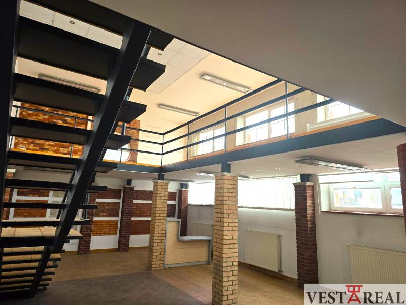 Beltéri üzlethelyiségek fa mintázatú padlóval és fém lépcsővel.