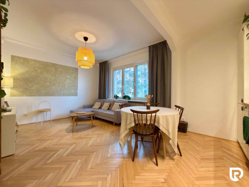 Nappali egy kétszobás lakásban barna kanapéval és fa dekoros padlóval.