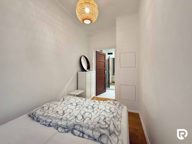 Hálószoba ággyal és fa dekorációjú padlóval egy kétszobás lakásban.