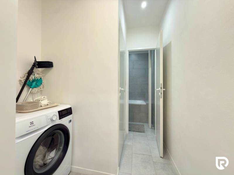 Mosógép a kétszobás lakás folyosóján, hozzáféréssel a fürdőszobához.