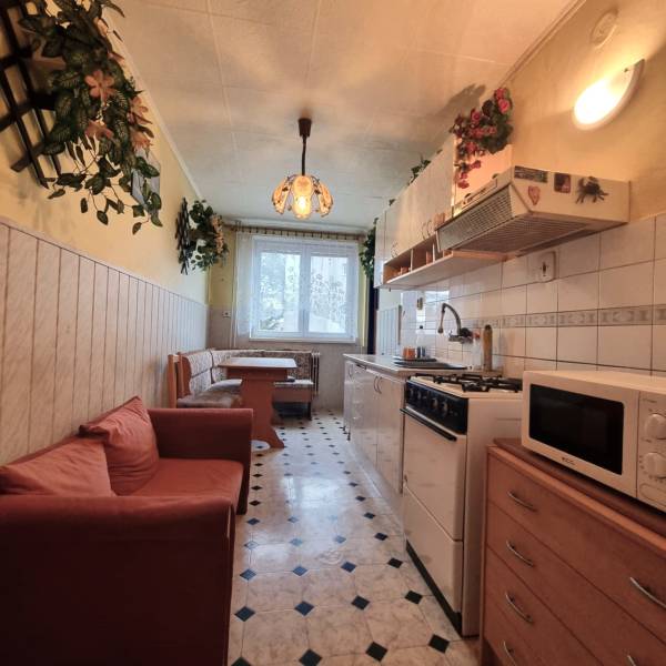 Konyha egy háromszobás lakásban étkező sarokkal, kanapéval és mintás padlóval.